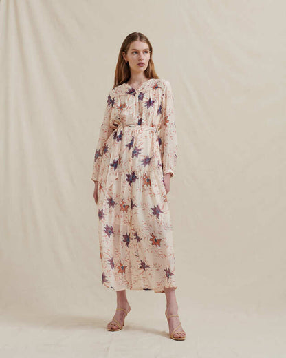 studio photo of a model wearing a long sleeve maxi dress in a cream colour with purple, blue, orange bloom print