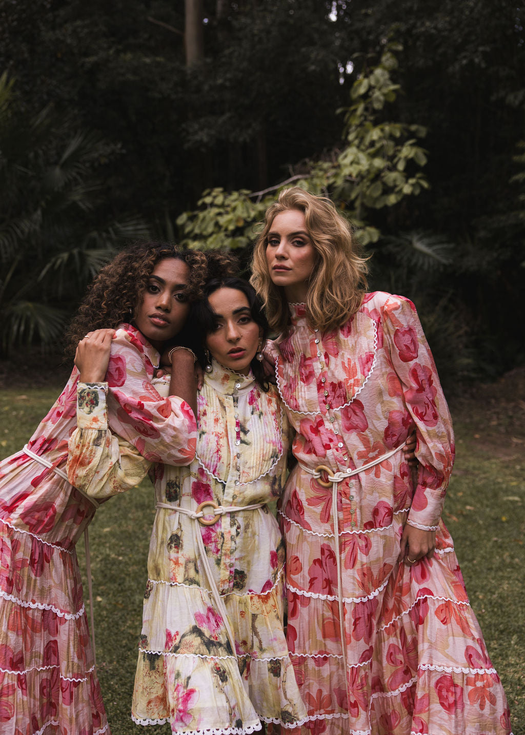 Tuscan Bloom campaign image by Analia the label of 3 beautiful women wearing romantic dresses with flowing gathered lace detailed tiers, long blouson sleeves in a viscose print of cream, peach, pink, yellow, ruby and olive blooms.